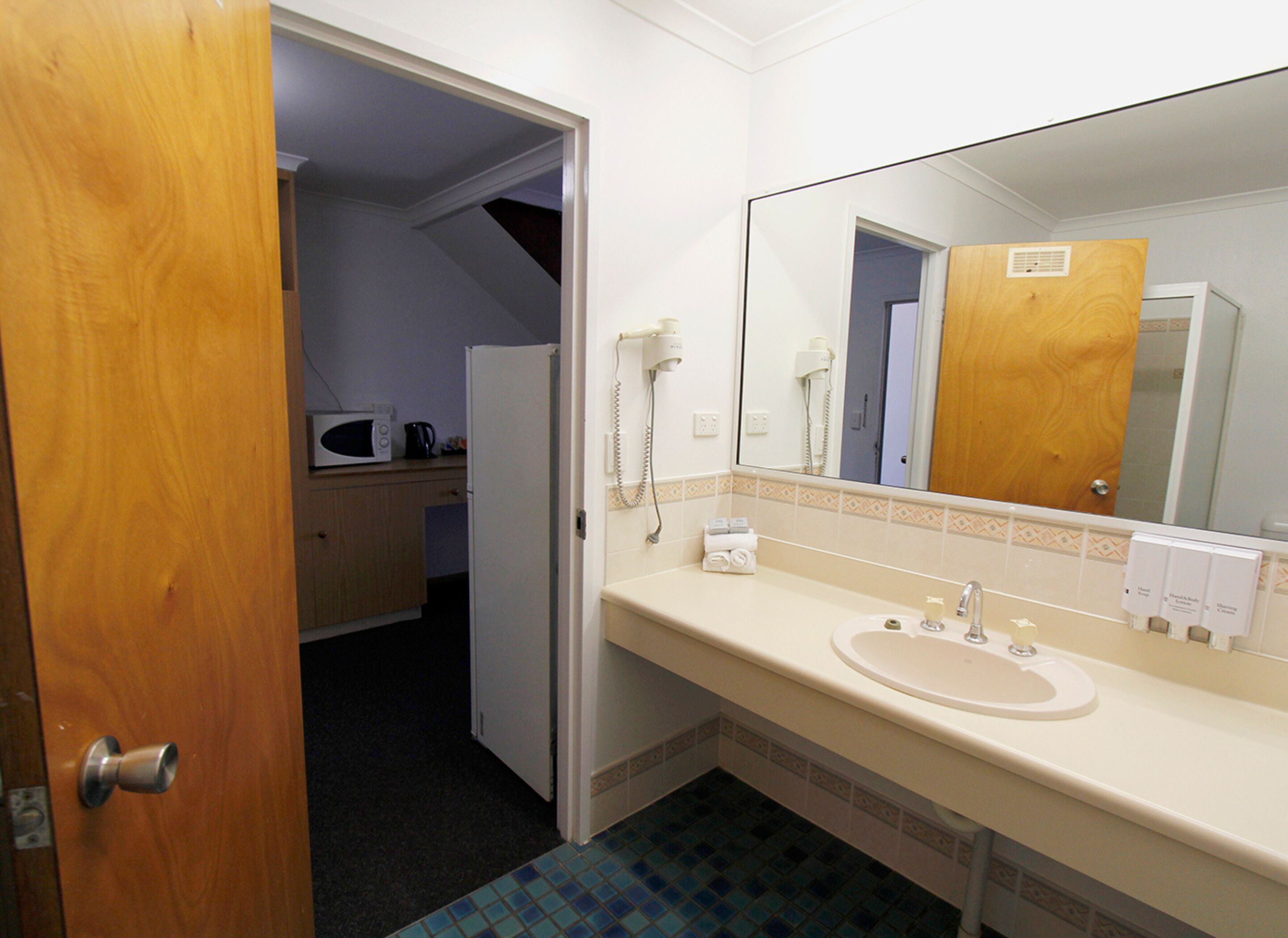 Un baño de hotel con lavamanos, espejo y secador de pelo.