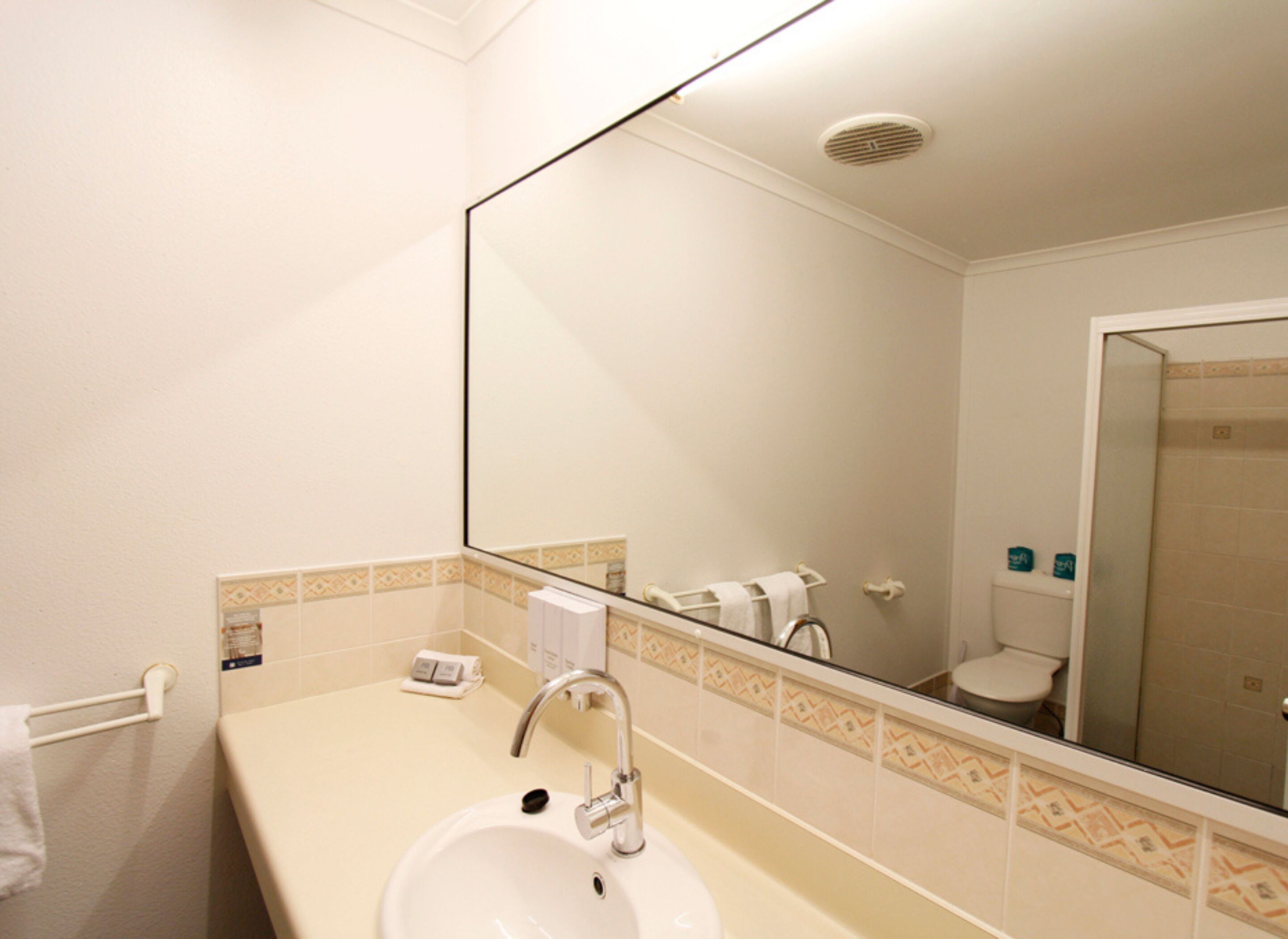 Un baño con lavamanos, espejo y retrete.