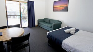 Une chambre d’hôtel avec un lit, un canapé, une table à manger et une chaise.