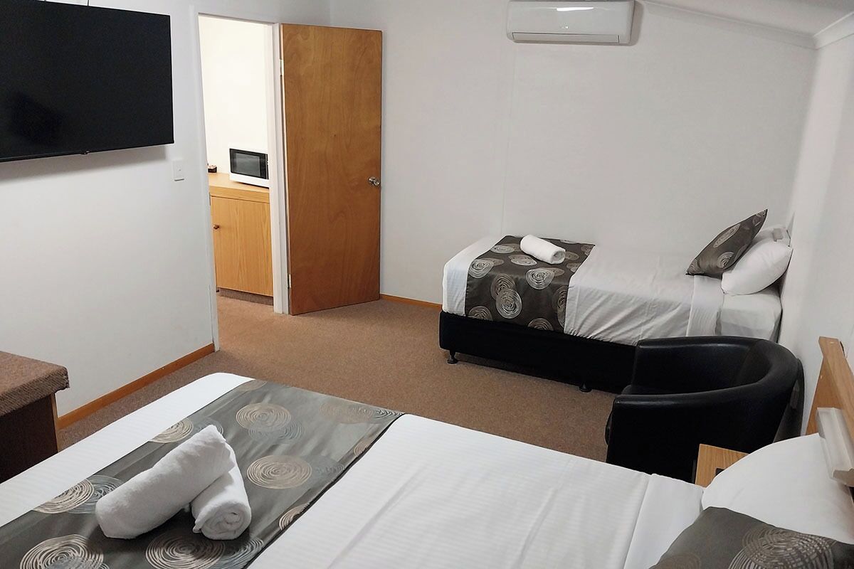 A hotel room with two beds, a TV, a desk, and a chair.