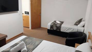 A hotel room with two beds, a TV, a desk, and a chair.