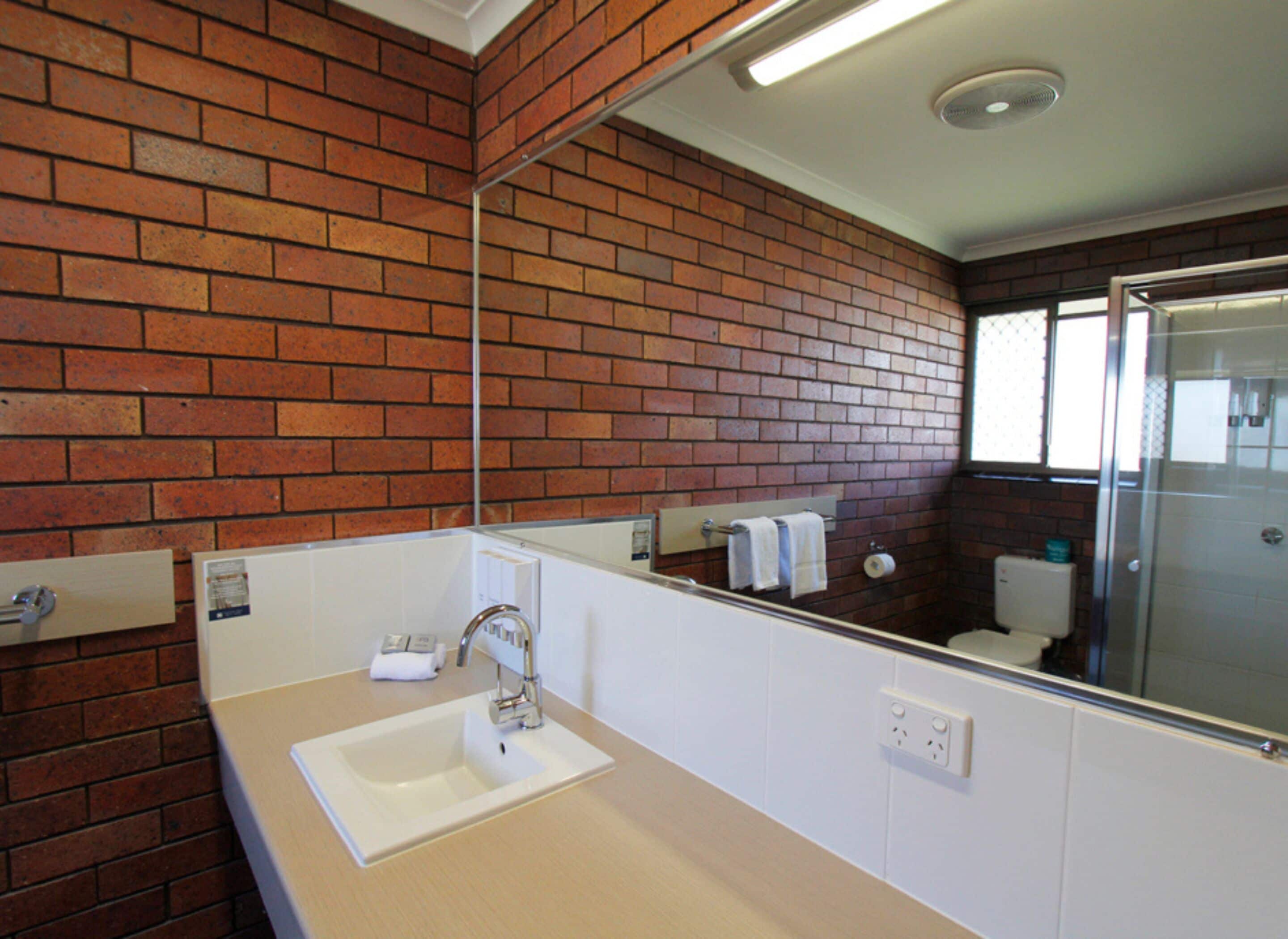 A bathroom with a white sink, a mirror, and a shower.