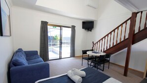 Une chambre d’hôtel avec un lit, un canapé, une table et un escalier.