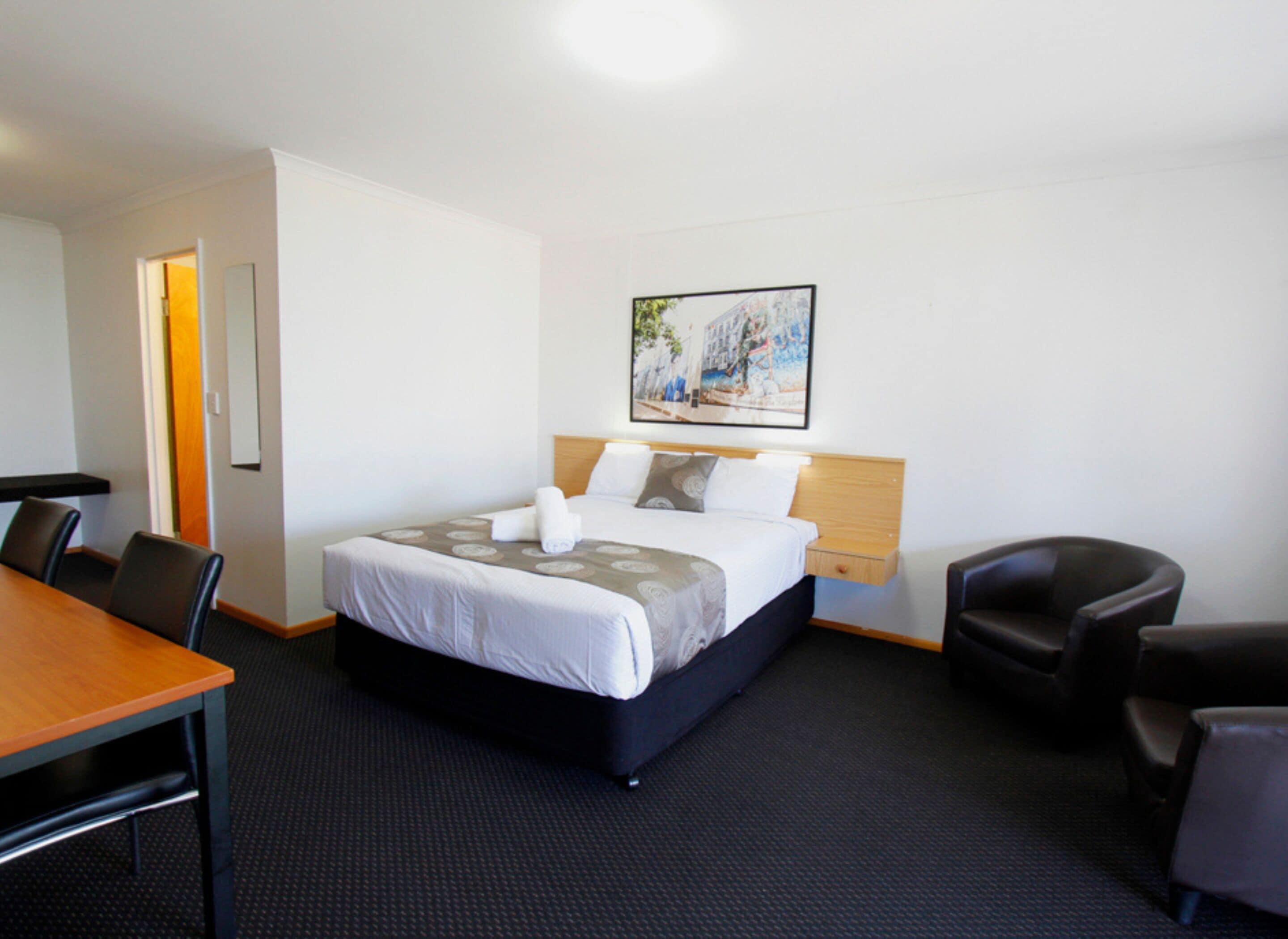 Une chambre d’hôtel avec un lit, un bureau et deux chaises.