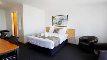 A hotel room with a bed, a desk, and two chairs.