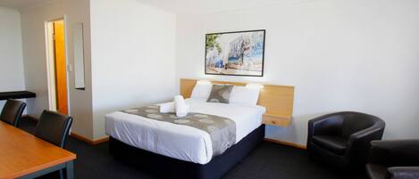 Une chambre d’hôtel avec un lit, un bureau et deux chaises.
