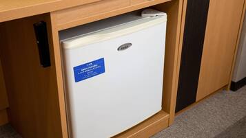 Refrigerador blanco y compacto con etiqueta azul debajo de una encimera de madera, que incluye un interruptor de encendido y un panel de control.