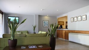 Un moderno vestíbulo de hotel con un sofá verde, una mesa de centro de madera y plantas en macetas.