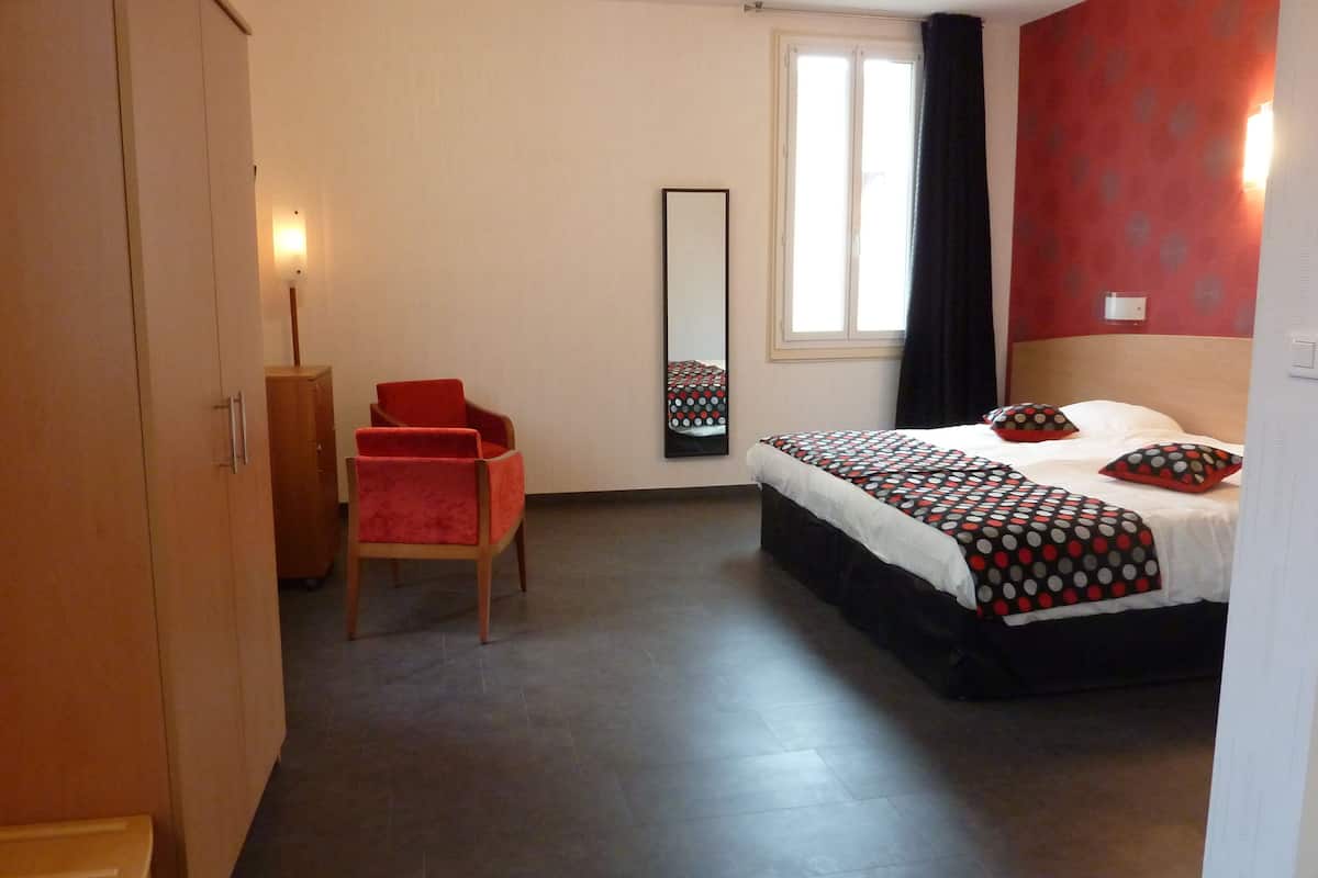 Une chambre à coucher avec un lit, une chaise, une armoire, un miroir et une fenêtre.