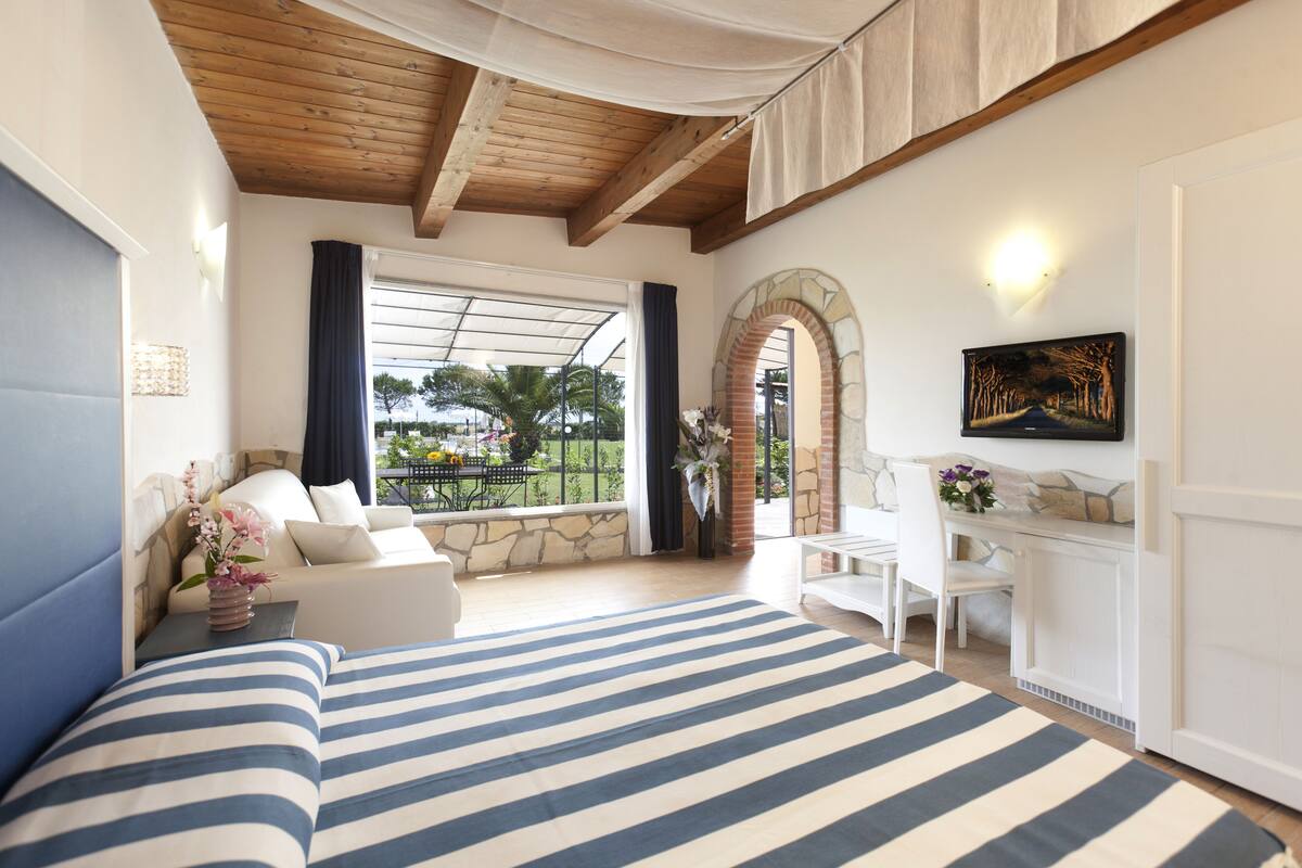A bedroom with a large bed, a desk, and a view of the outdoors.