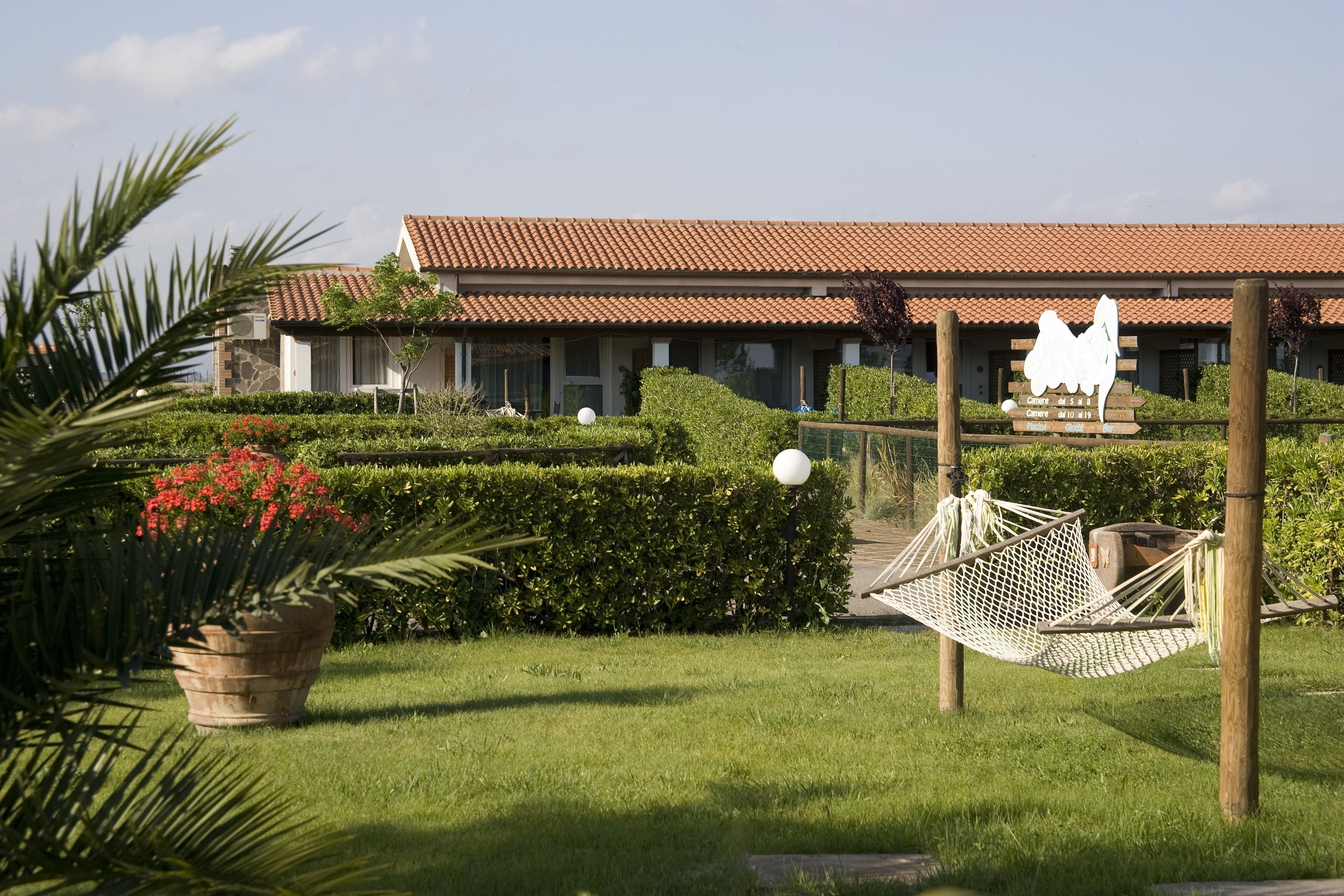 A hotel with a tiled roof, a hammock, and a sign with a bear and a dog.