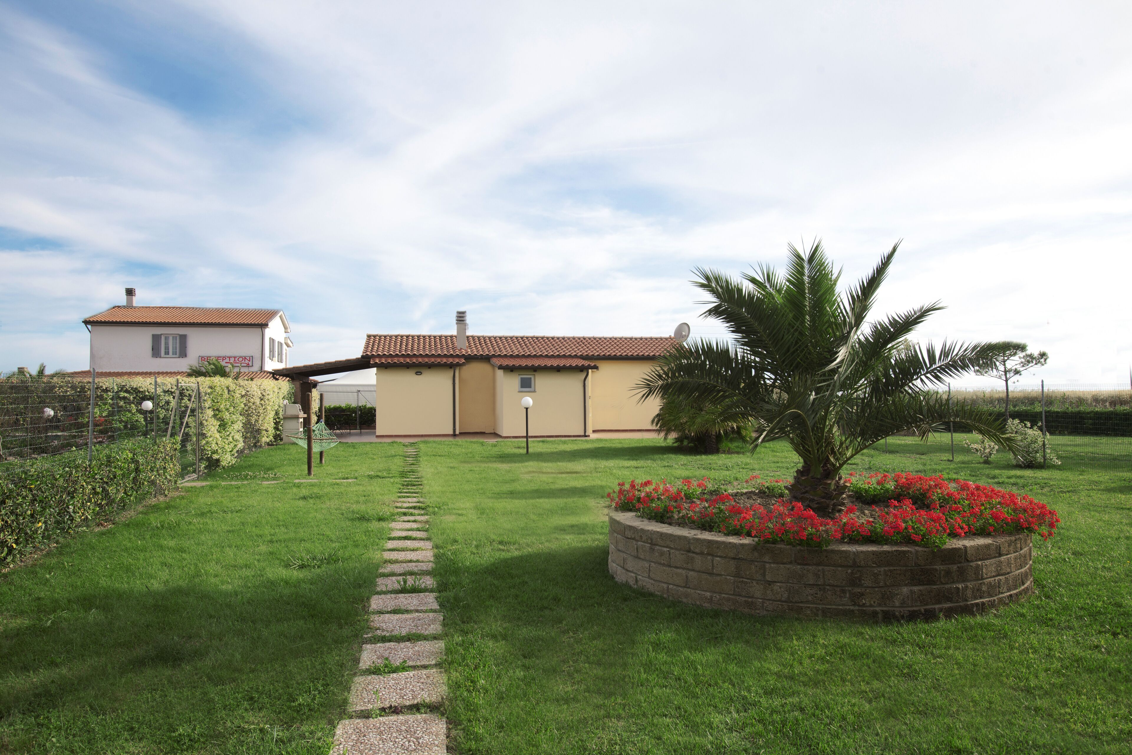 A well-maintained garden with a pathway leading to a building with a tiled roof.