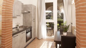 Una cocina con un arco de piedra, una mesa de comedor con sillas y vistas al exterior a través de un ventanal.