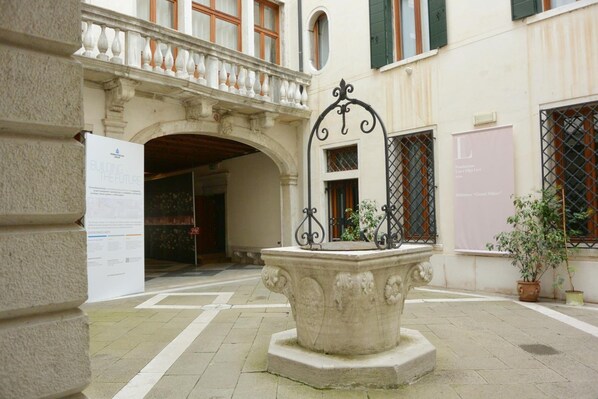 A courtyard with a central fountain, a building entrance, and potted plants.