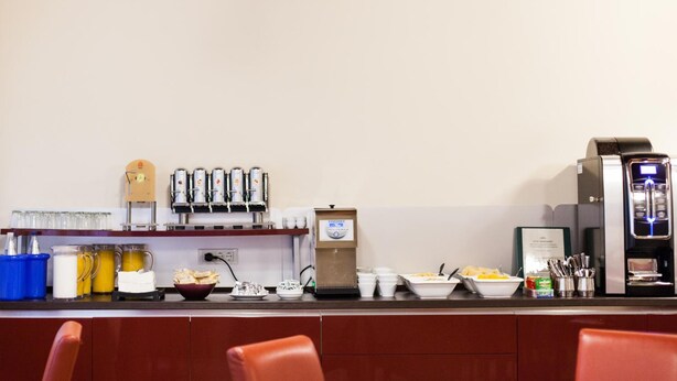 A breakfast bar with coffee machines, a juice dispenser, and various breakfast items. - Foresteria Levi (Venice)