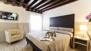 Une chambre d’hôtel avec un lit, une chaise, une télévision et une table de chevet avec une lampe.