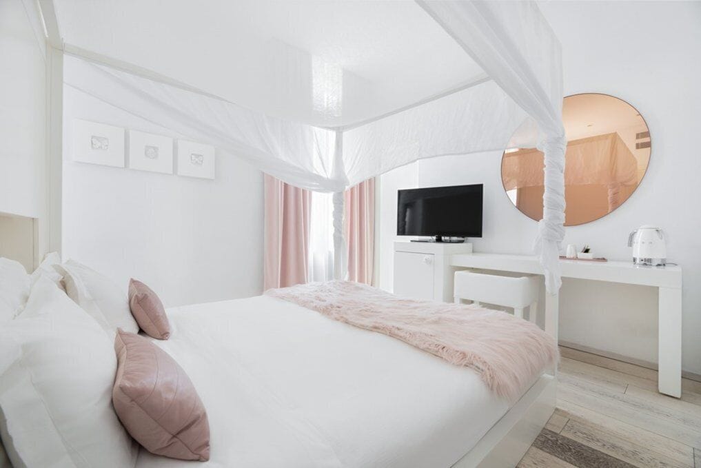 Ein Schlafzimmer mit Bett, Nachttisch, Fernseher und einem runden Spiegel.