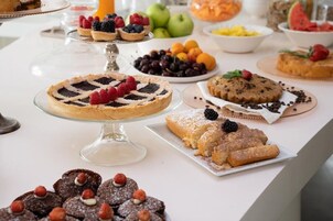 Un'ampia scelta di dolci su un tavolo buffet, tra cui torte, crostate e pasticcini.