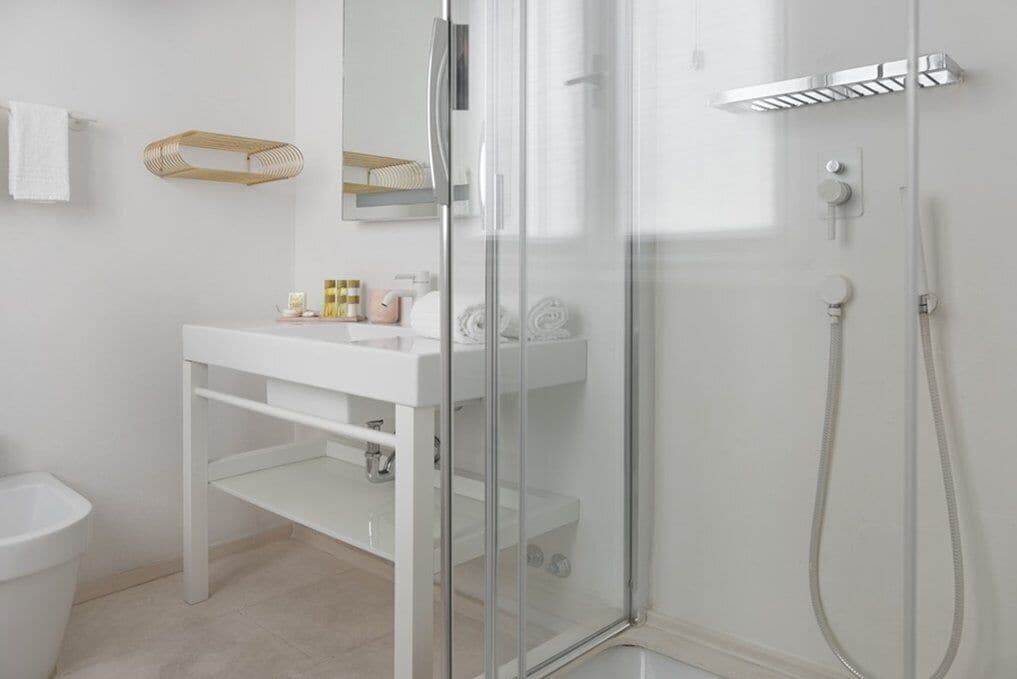 A modern bathroom with a white sink, glass shower enclosure, and a white toilet.