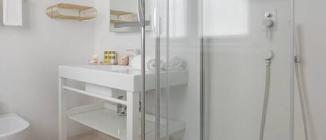 A modern bathroom with a white sink, glass shower enclosure, and a white toilet.