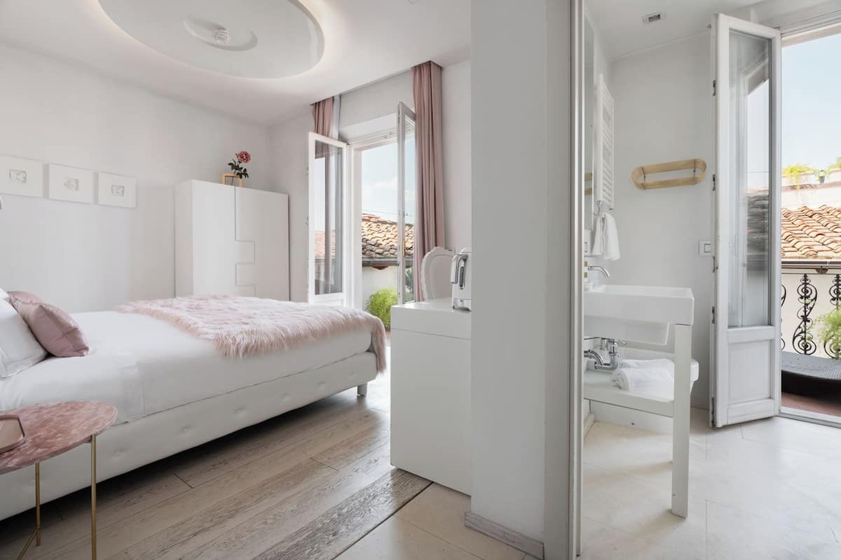 A modern bedroom with a bed, a vanity, and a balcony.