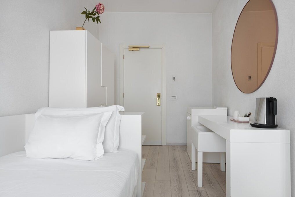 A modern hotel room with a bed, a desk, and a large mirror.