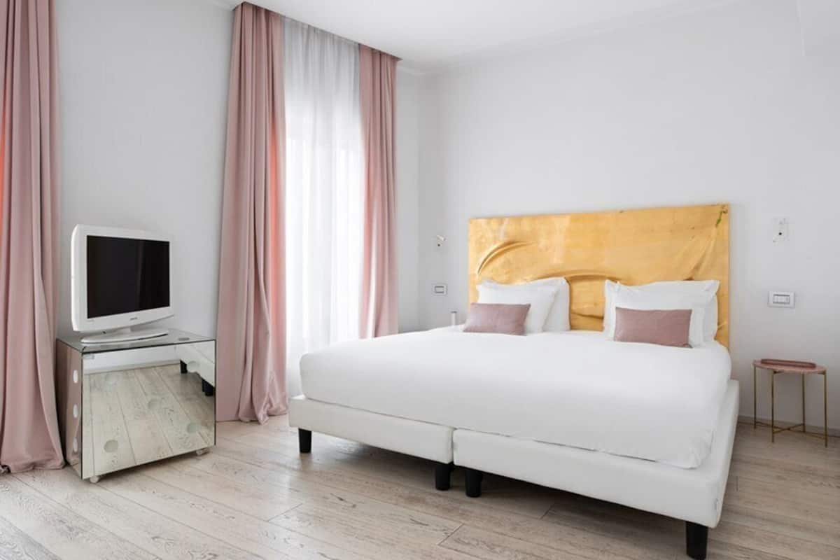 A bedroom with a bed, a television on a cabinet, and curtains.