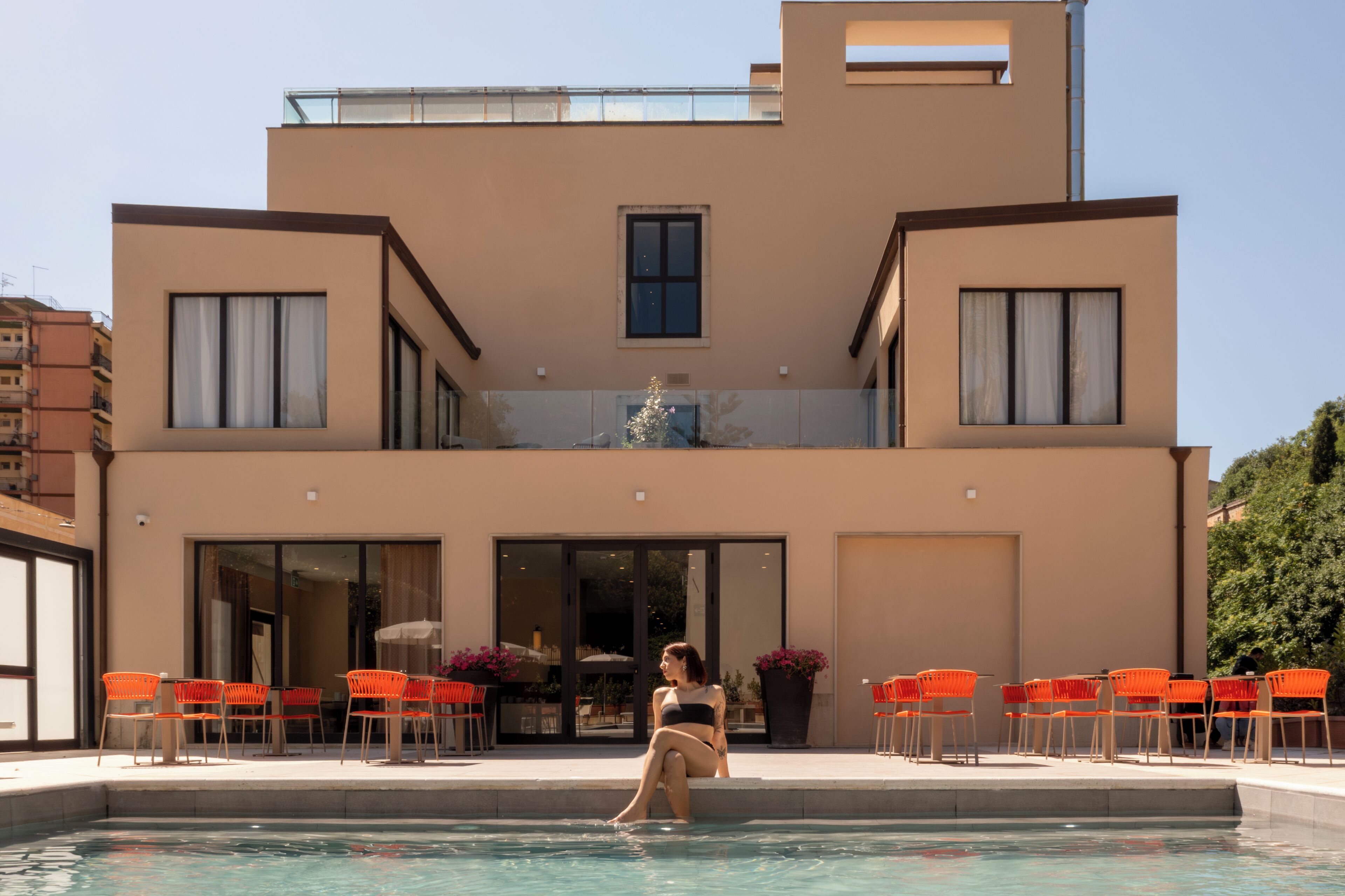 A modern two-story building with a swimming pool in front.