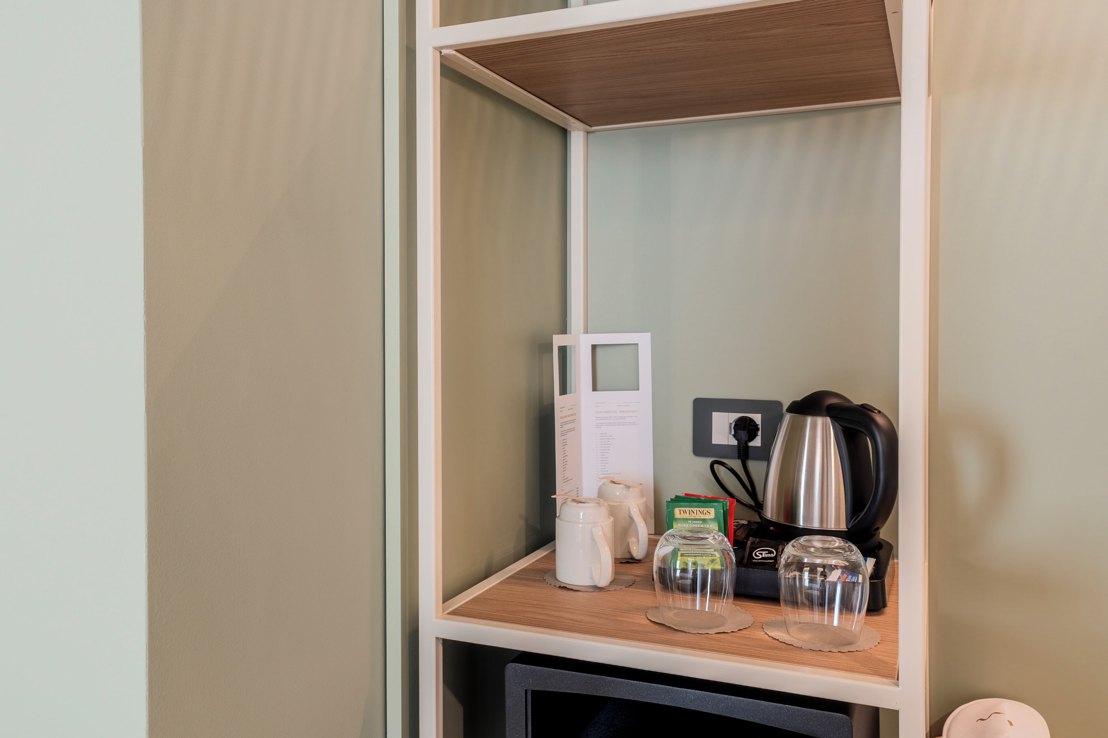 A shelf with a kettle, a coffee maker, and a glass jar.