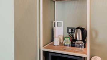 A shelf with a kettle, a coffee maker, and a glass jar.