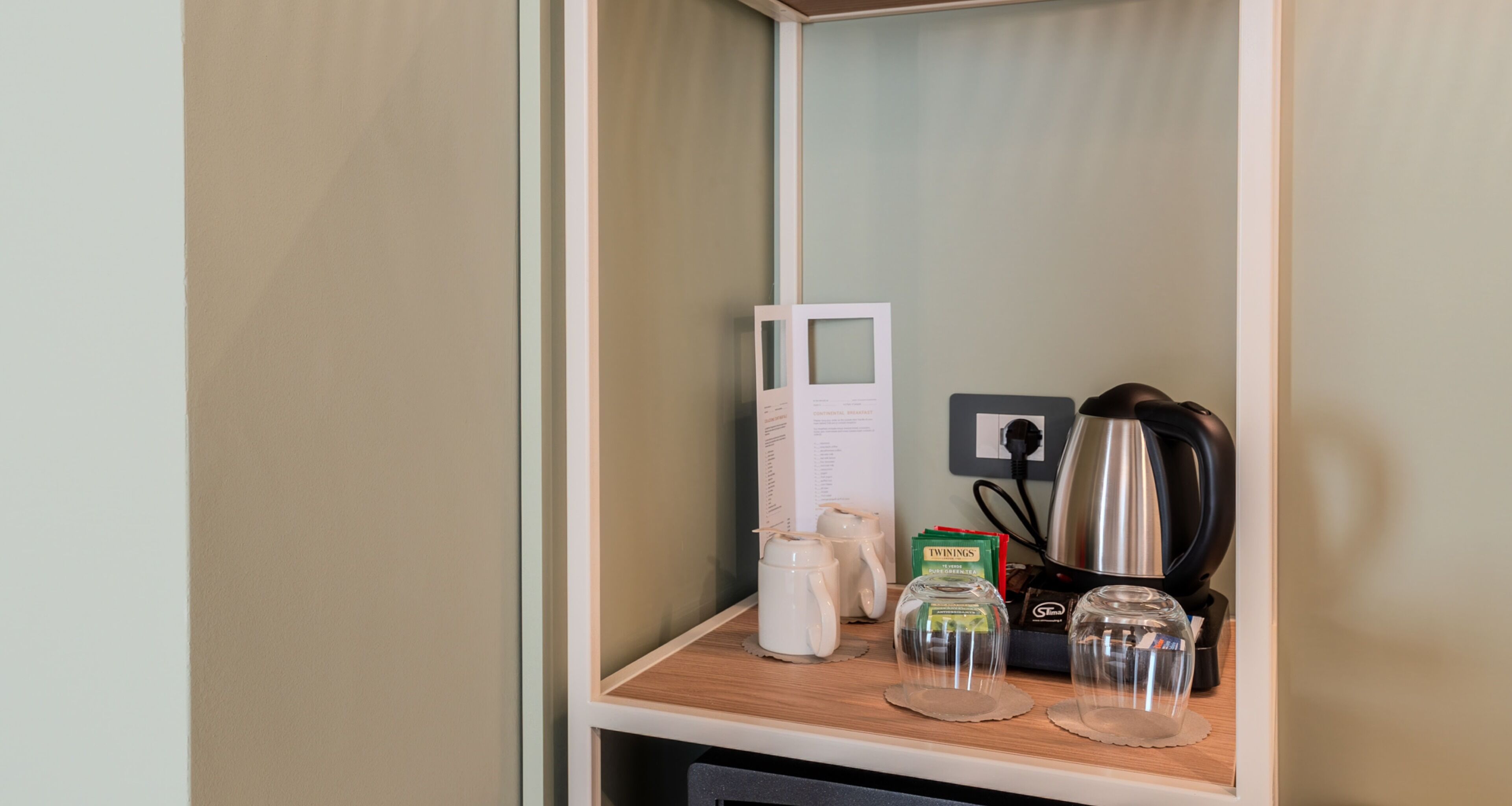 Un angolo cottura con una macchina del caffè, un bollitore e un menu appeso al muro.