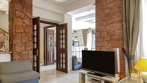 Una sala de estar moderna con un pilar de piedra, un sofá, un televisor de pantalla plana y una mesa de centro de vidrio.
