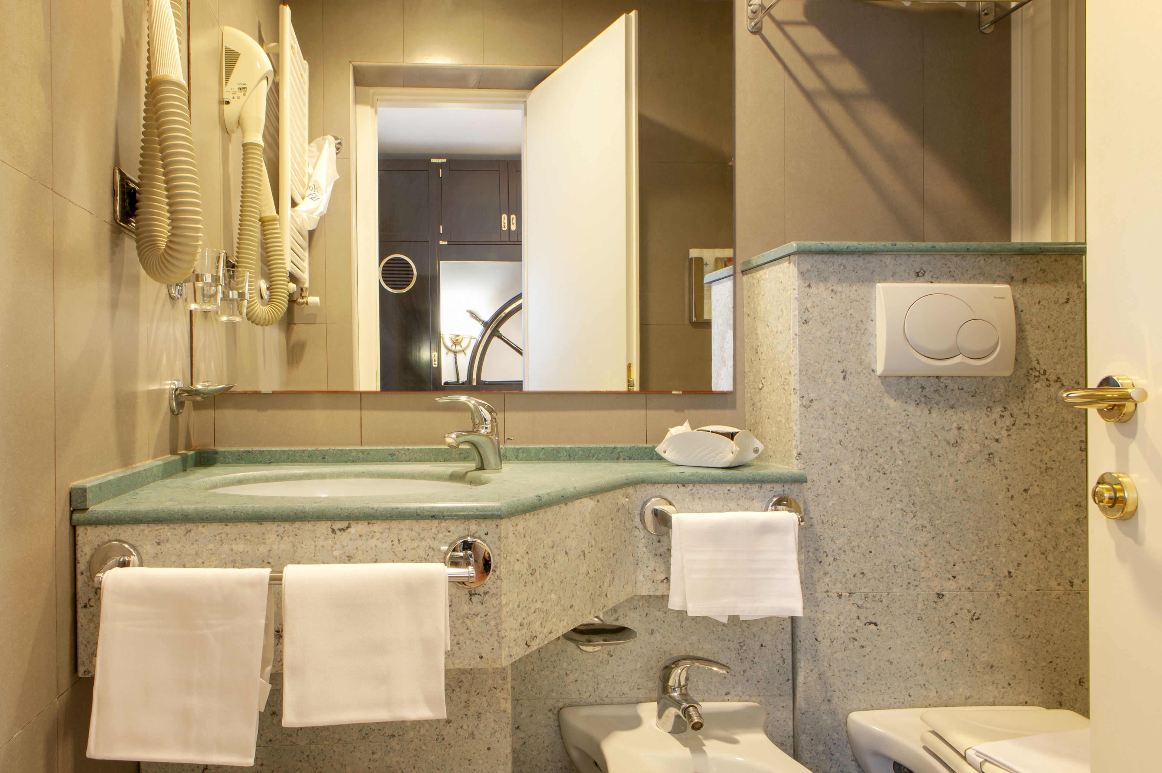 A modern bathroom with a granite countertop, a sink, a toilet, and a mirror.
