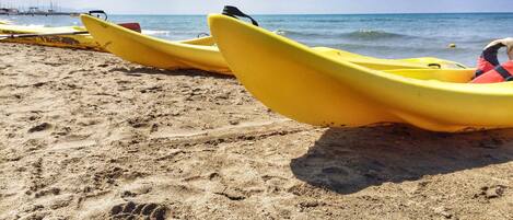 A sandy beach with yellow kayaks lined up.