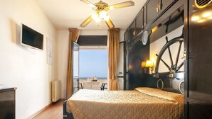 Habitación de hotel con cama, escritorio, silla, televisión, ventana y vista al mar.