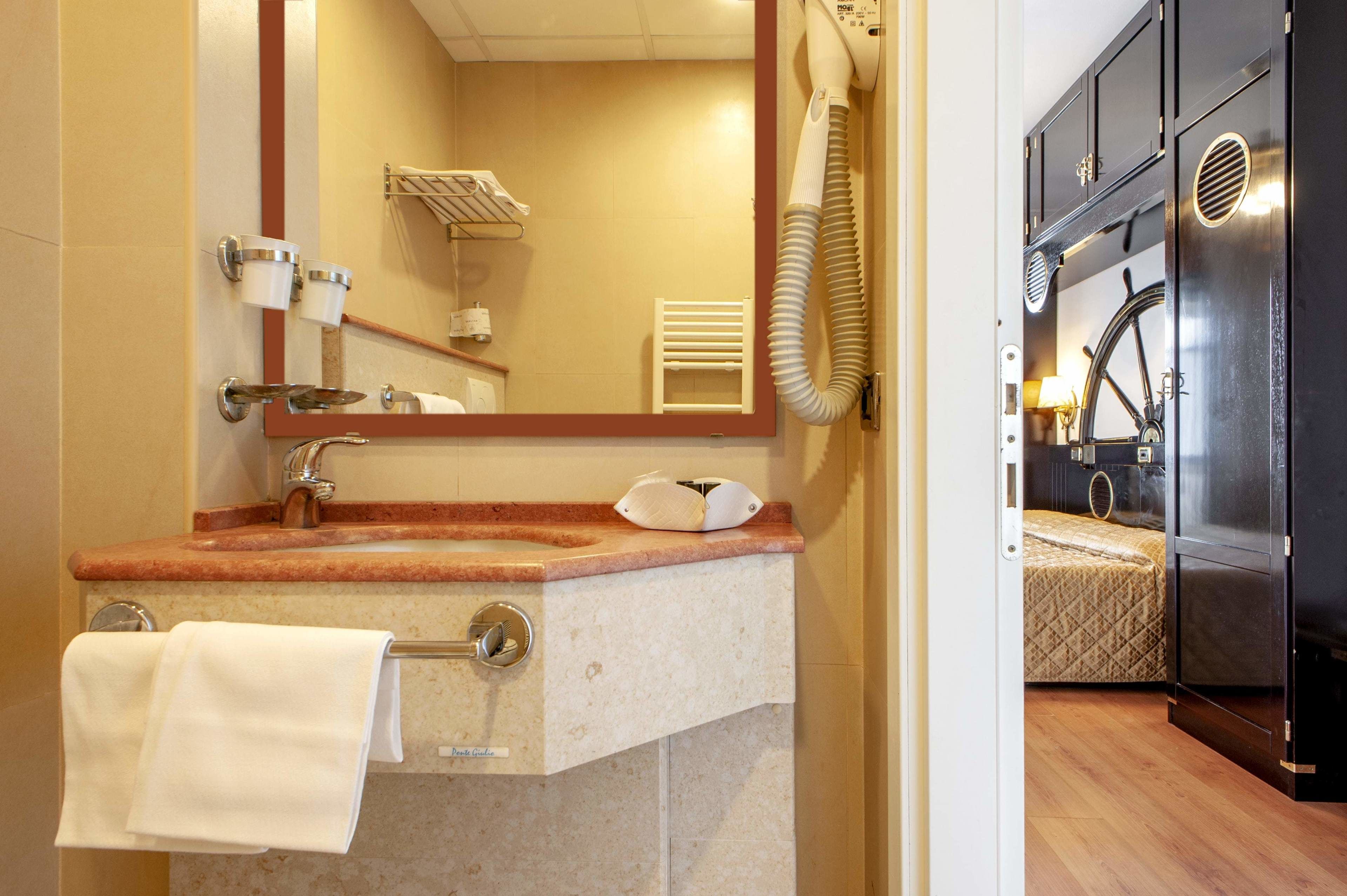 A bathroom with a sink, mirror, towel rack, and a hairdryer.