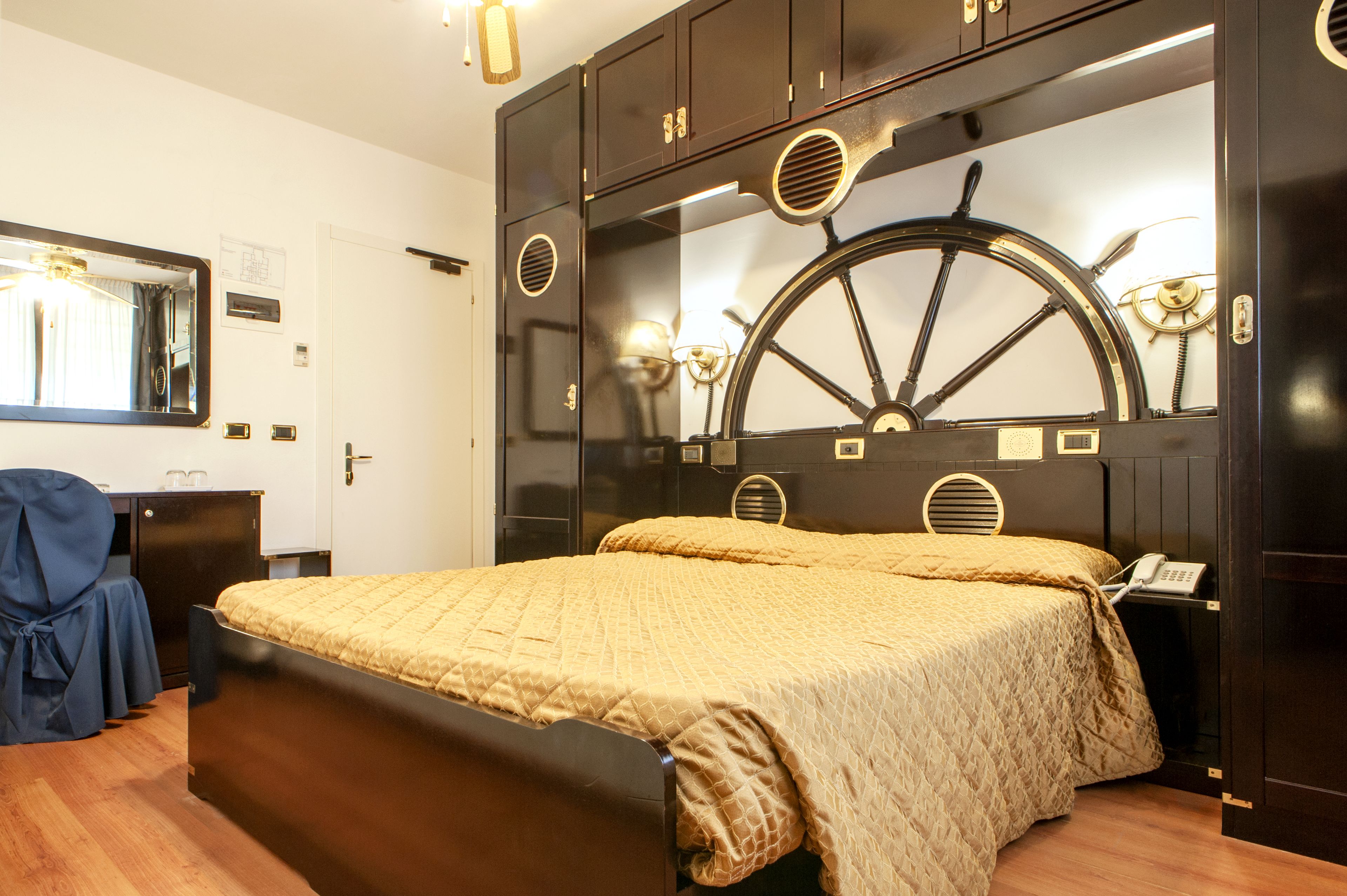 A bedroom with a bed, a wardrobe, a desk, and a mirror.