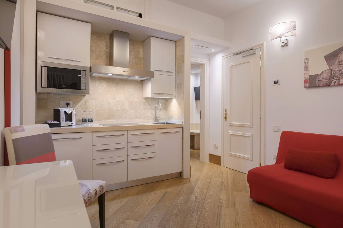A compact living space with a kitchenette, a red sofa, and a dining area.