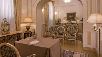 Une salle à manger élégante, avec une table dressée pour six personnes, des chaises richement décorées et un lustre.