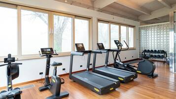 Un gimnasio con cintas de correr, elípticas y un soporte para pesas.