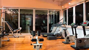 Un gimnasio con equipo de ejercicio, ventanas amplias y piso de madera.