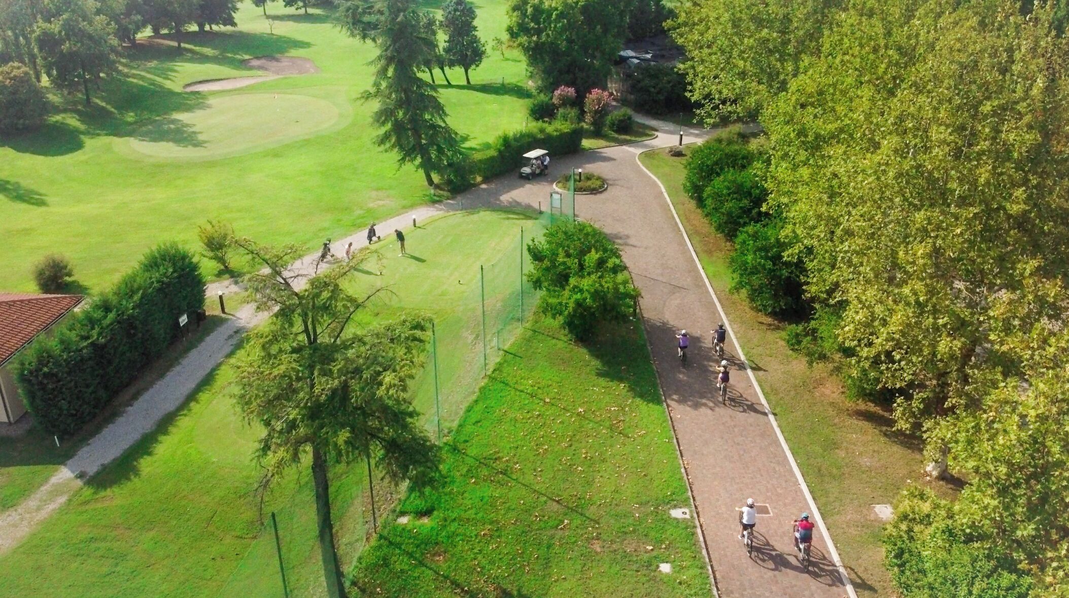 Eine Vogelperspektive auf einen Golfplatz mit einem Fußweg, Bäumen und einem kleinen Gebäude.