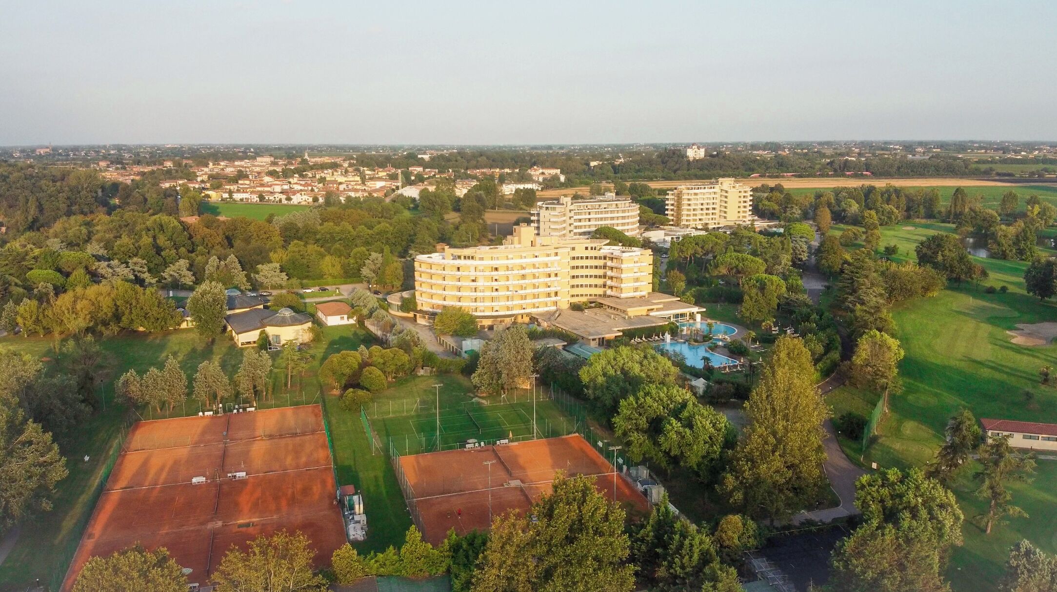 Un grand hôtel composé de plusieurs bâtiments, entouré d’espaces verts et d’un parcours de golf.
