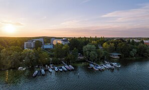 Vista del lago con barcos amarrados, edificios y árboles.
