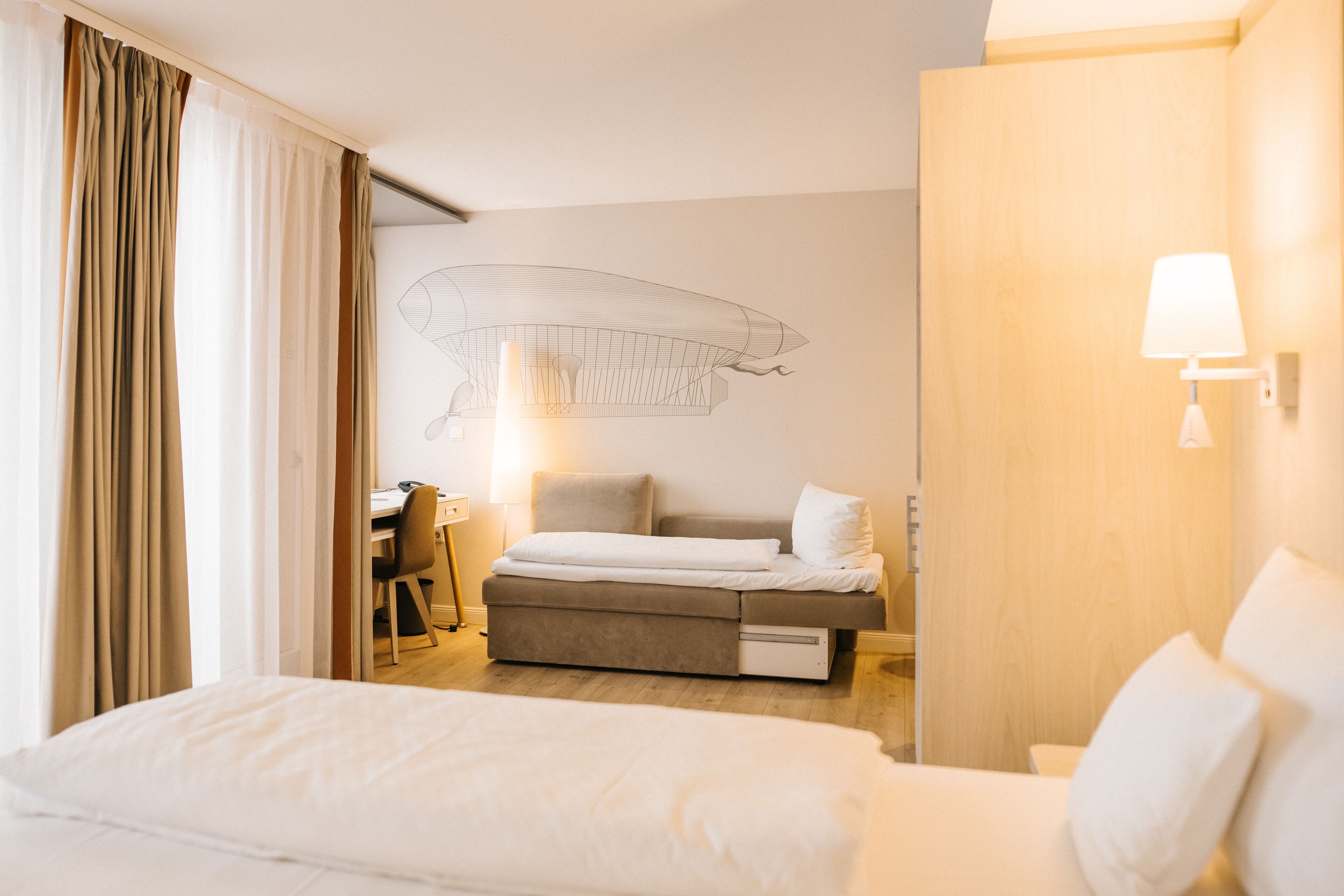 A hotel room with a bed, a desk, and a chair.