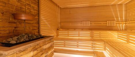 Una sauna con bancos de madera y pared de piedra.