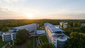 Een modern hotel met een gebogen dak, meerdere balkons en een terras op het dak.