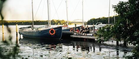 A dock with boats, a bridge in the background, and a calm water surface with lily pads.