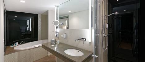 Un baño moderno con una bañera grande, un lavamanos independiente y cabina de ducha con paredes de vidrio.