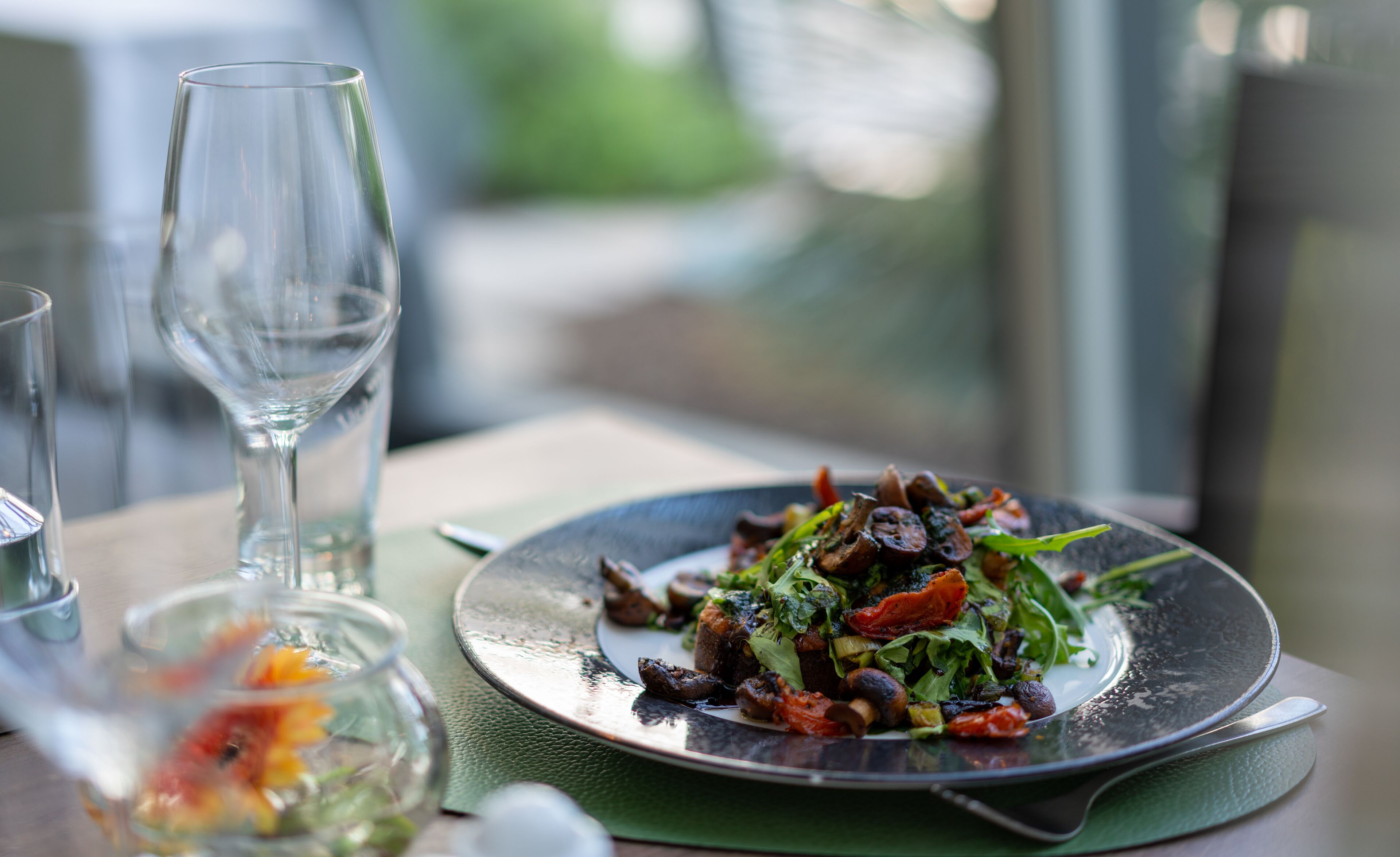 A dining table with a plate of food, a glass of water, and a glass of wine.